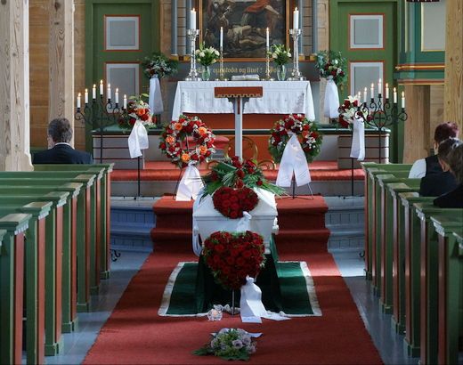 Foto av kiste med blomar framfor alteret i Tjugum kyrkje